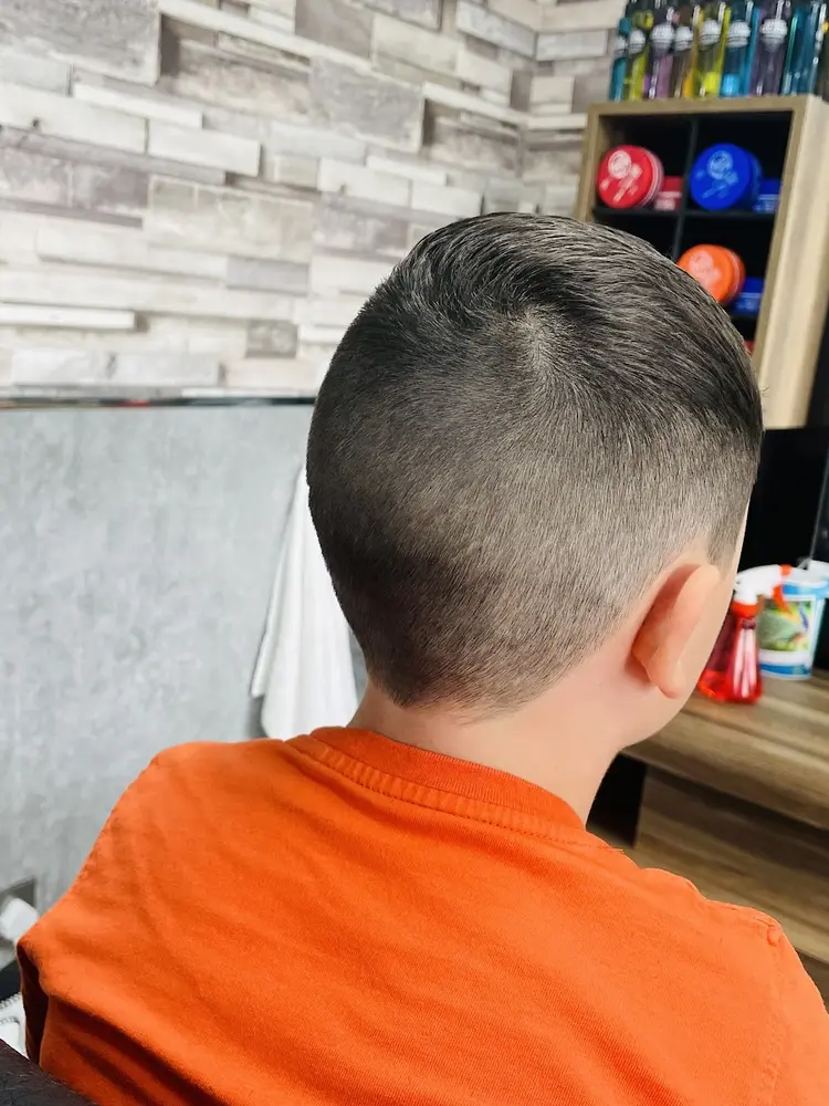 A young boy in an orange t-shirt after a fresh short back and sides